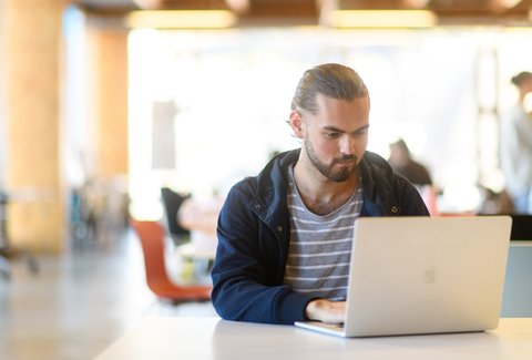 Student sitting down using laptop in common area.