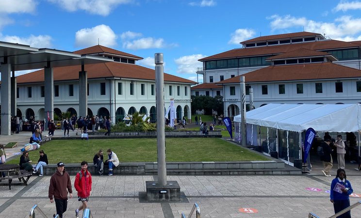 Auckland Open Day 2023. Students walking around campus with Open Day tent in the background.
