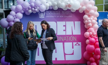 A group in front of an Open Day sign and balloons.