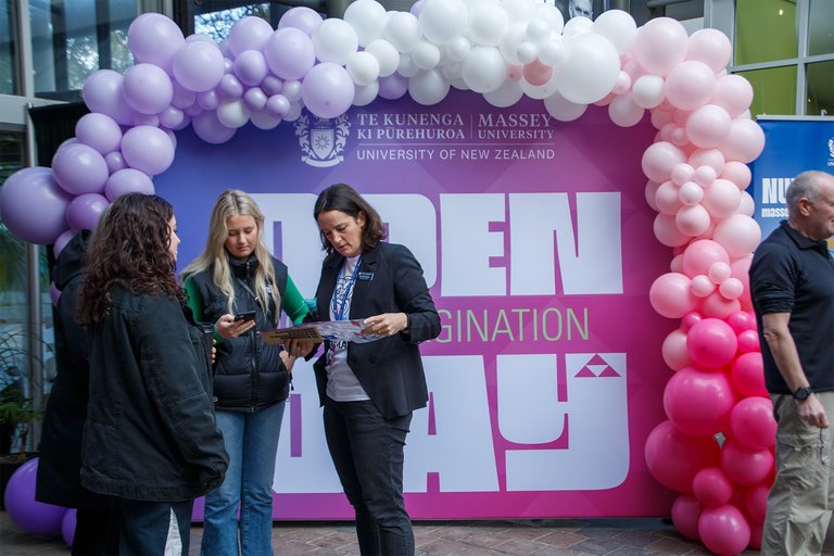 A group in front of an Open Day sign and balloons.