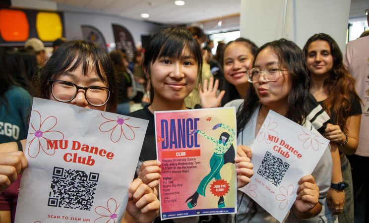 Clubs day at Orientation in Palmerston North. Three students holding flyers about clubs on campus.