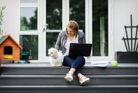A woman studies at home with her dog
