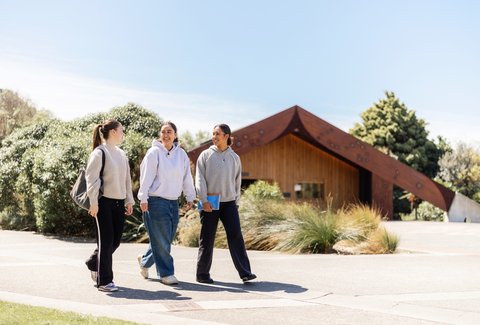 Three students walking on Wellington campus outside marae.