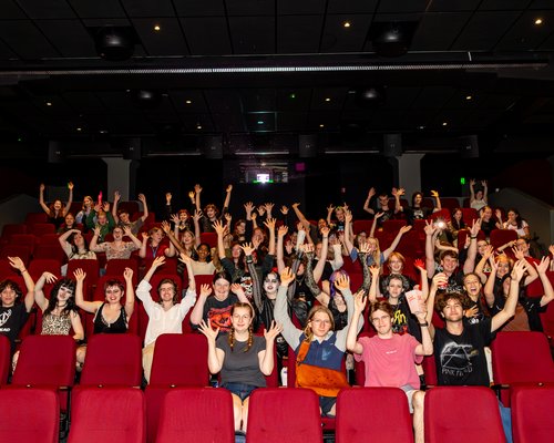 Orientation movie night on Wellington campus. Group of students lifting there arms waving to the camera.