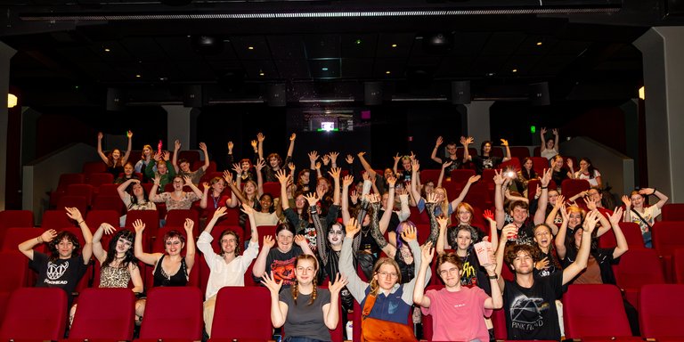 Orientation movie night on Wellington campus. Group of students lifting there arms waving to the camera.