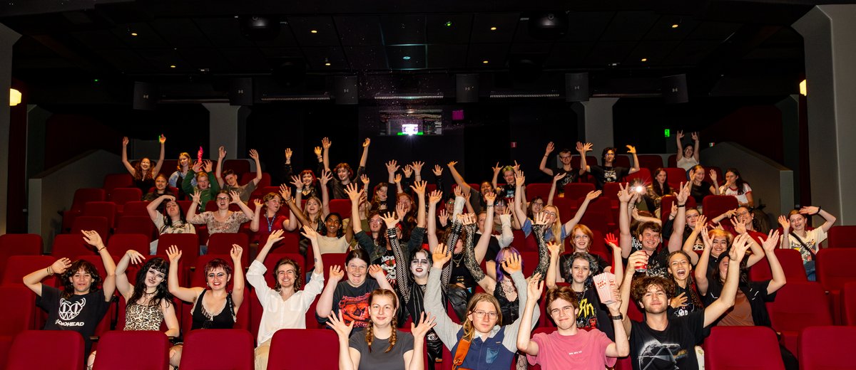 Orientation movie night on Wellington campus. Group of students lifting there arms waving to the camera.