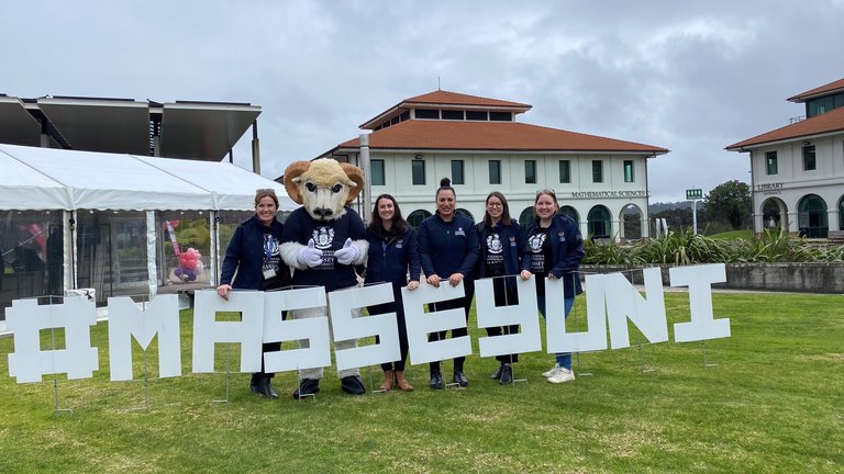 Open Day in Auckland 2024 - The events team and Fergus with MasseyUni sign