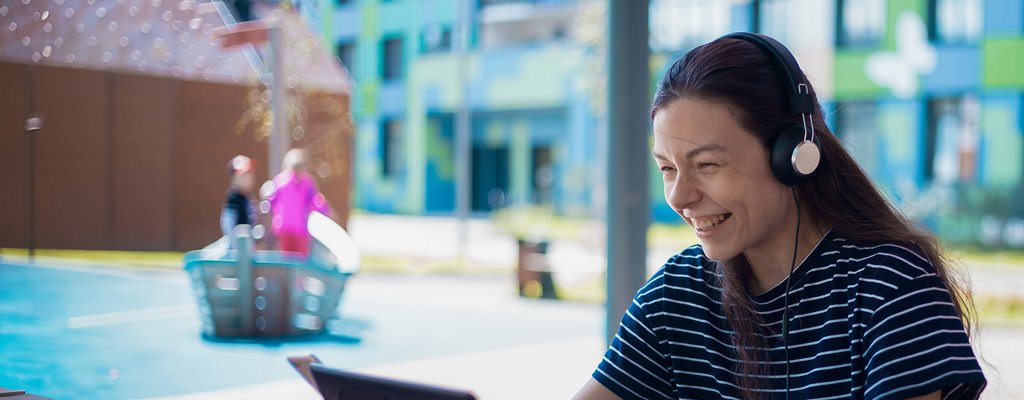 Student smiling looking at laptop with headset on.