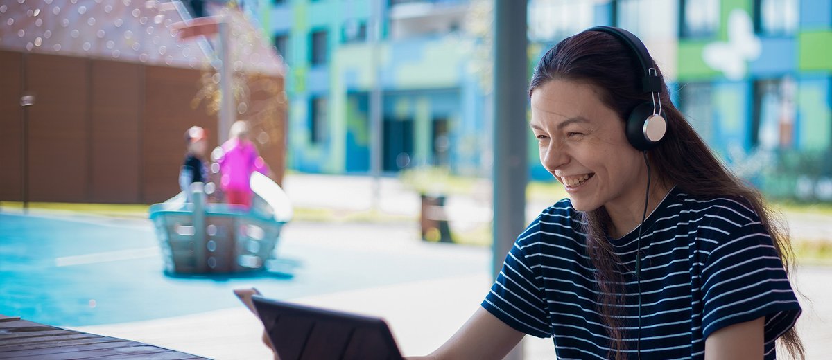 Student smiling looking at laptop with headset on.