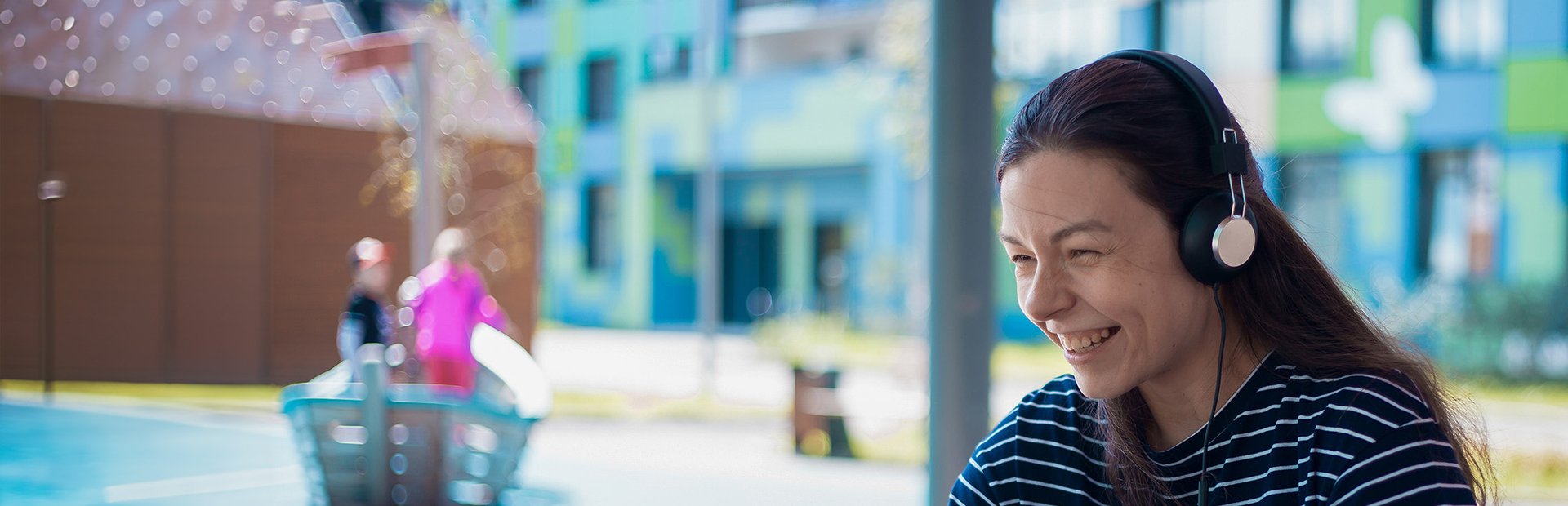 Student smiling looking at laptop with headset on.