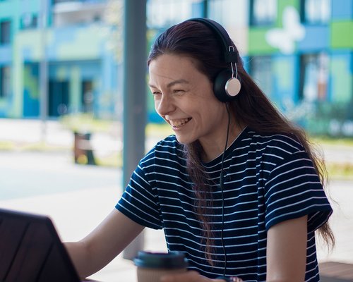 Student smiling looking at laptop with headset on.