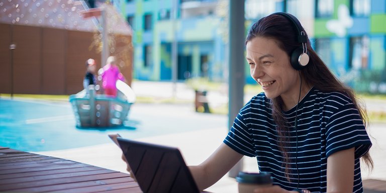 Student smiling looking at laptop with headset on.